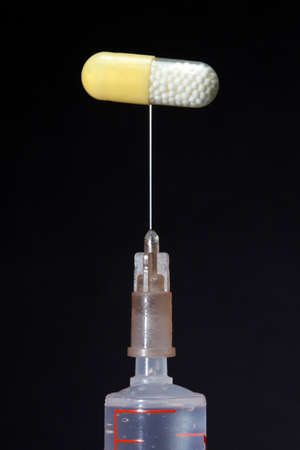 medical syringe with a needle and a pill on dark backgroundの写真素材