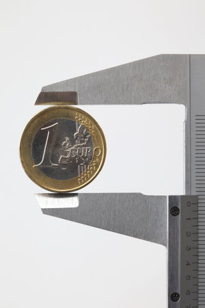 euro money coin sized by vernier tool on white backgroundの写真素材