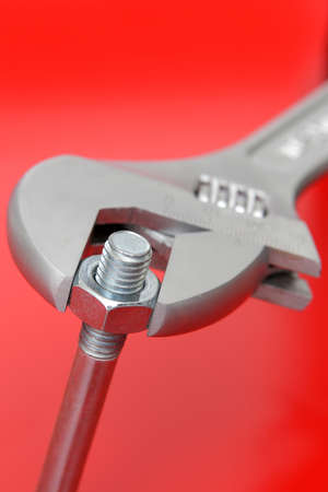 Wrench and bolt on red background の写真素材