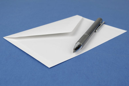 Envelope with pen on blue backgroundの写真素材