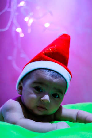 close up image of cute baby boy. wearing Christmas hat. noise for artistic look.の写真素材