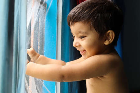 Indian small standing at window and smiling. soft skin effect. use as background.の写真素材