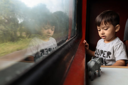 three year old cute baby, sitting at window seat, playing with plastic animal toys