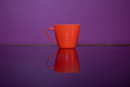 Orange tea and coffee cup on table, reflection on glass