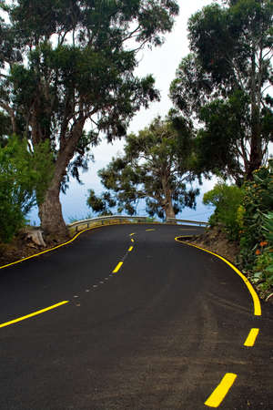 a dangerous curve in a winding mountain road with yellow marks jの写真素材
