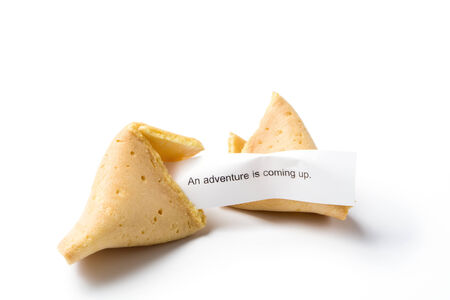 a broken fortune cookie isolated on white with message "an adventure is coming up"の写真素材