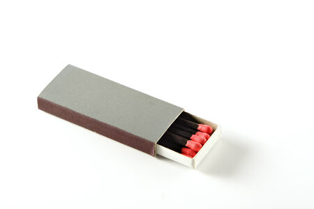 half opened slim grey matchbox containing black matches with red headsの写真素材