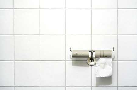 Toilet paper holder with two rolls, one empty, one with a single leaf の写真素材