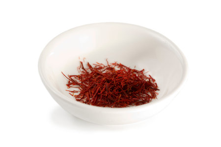 small white bowl filled with saffron stigmas isolated on white backgroundの写真素材