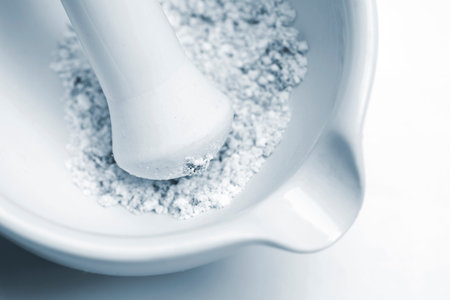 close-up of laboratory pestle in mortar with ground material, blue toned