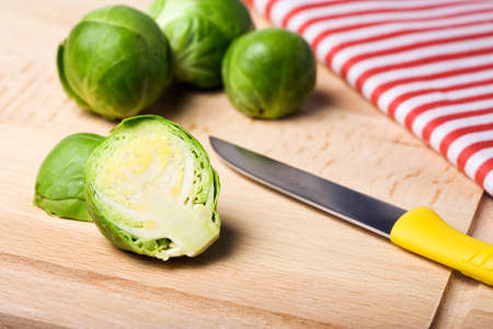 brussels sprout, kitchen knife and towel on wooden boardの写真素材
