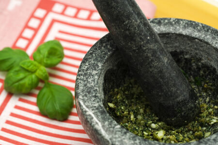 pesto sauce in granite mortar, basil leaves and towel in backgroundの写真素材