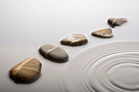 striped pebbles forming a curve in rippled water surface