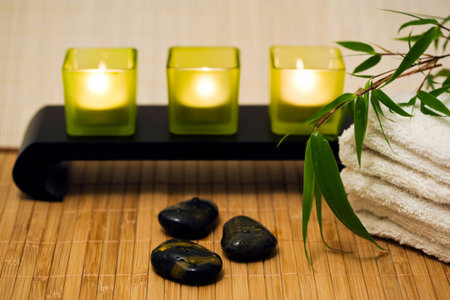 still-life with spa accessories - candles, hot stones, towel, bamboo branchの写真素材