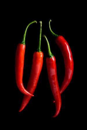 four red chilim peppers on black backgroundの写真素材