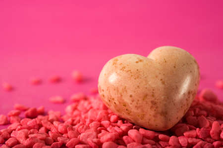 heart shaped stone on pink gravel, purple backgroundの写真素材