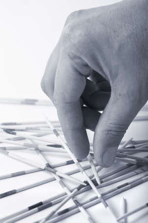hand carefully picking mikado game stick, black and white, blue tonedの写真素材