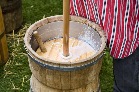 man making butter in a plunger-type butter churnの写真素材
