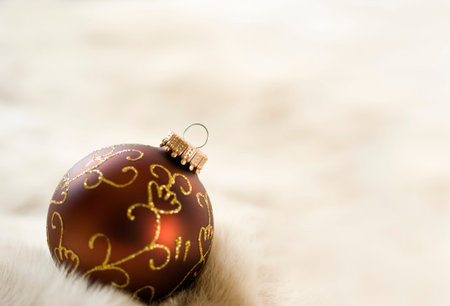 ornate brown and golden christmas bauble on fur, selective focus, large copy spaceの写真素材