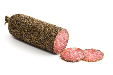 peppered salami sauage with slices isolated on whiteの写真素材