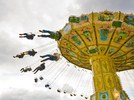 people riding the spinning swing at fairgroundの写真素材