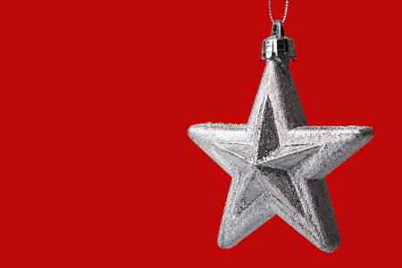 silver star shaped christmas tree decoration isolated on red backgroundの写真素材