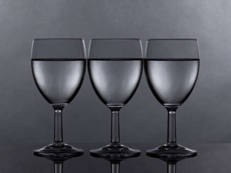 three glasses of white wine or water filled to the same levelの写真素材