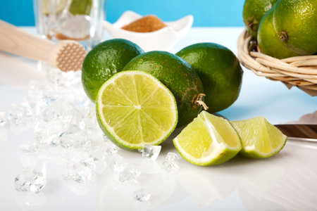 ingredients for caipirinha cocktail - limes, crushed ice, brown sugar