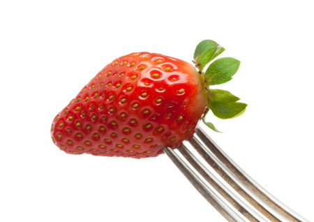 closeup of strawberry on fork tines, white backgroundの写真素材