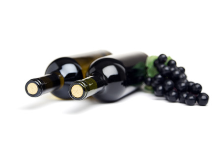 two bottles of wine and black grapes on white background, shallow depth of fieldの写真素材