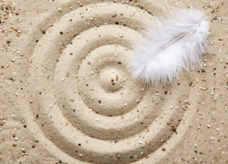 white feather on sand circlesの写真素材