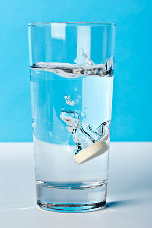 vitamin pill drowning in a glass of waterの写真素材