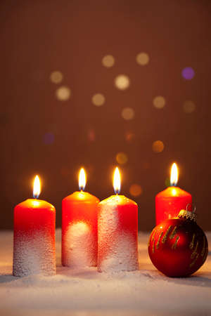 four burning advent candles and a christmas tree bauble on snow, shallow depth of fieldの写真素材