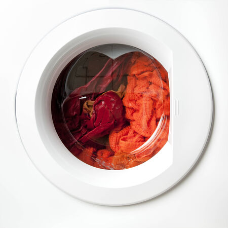 red and orange laundry being washed in a washerの写真素材