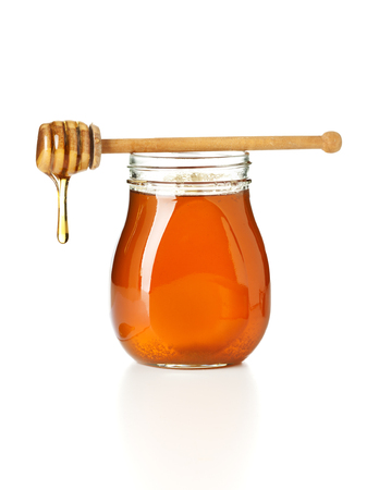 honey dripping from drizzler on top of jar, siolated on white backgroundの写真素材