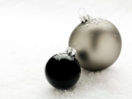 black and silver christmas baubles in snowの写真素材