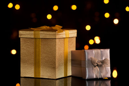 Golden and silver gift boxes with christmas lights in backgroundの写真素材
