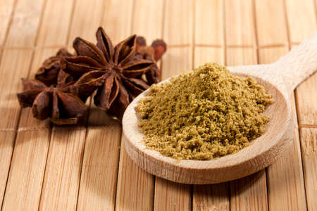 Anise, whole stars behind wooden spoon with a heap of powderの写真素材