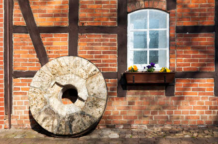 Old millstone standing in front of half-timbered buildingの写真素材