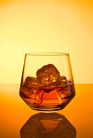 Whisky and ice cubes in tumbler, warm lightingの写真素材