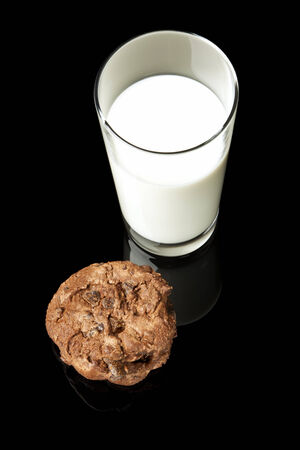 Glass of milk and chocolate chip cookies on black backgroundの写真素材