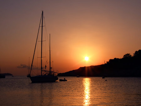 silhouette of a sail boat at Cala Salada, Ibiza, at sunsetの写真素材
