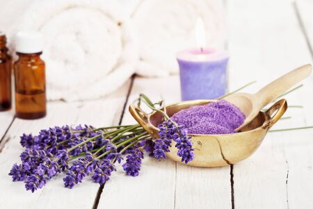 lavender flowers, bath salt, massage oil, scented candle and towels on rustic white background, high key imageの写真素材