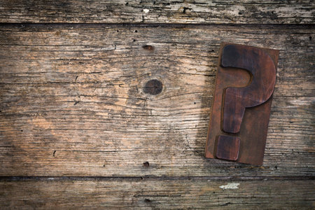 question mark vintage letterpress printing block on rustic wood background, copy space on left sideの写真素材