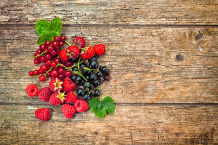 assorted berries on rustic wood background with copy space
