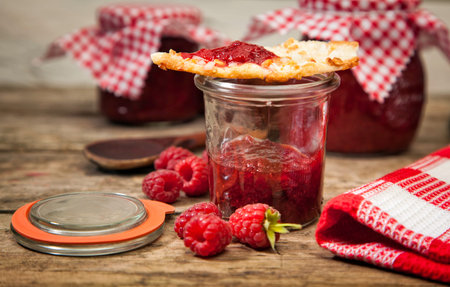 Handmade raspberry jam in a jar with almond cake on top
