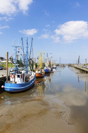 Fishing boats at the harbor of Dorum on the wadden sea coast at low tideの写真素材