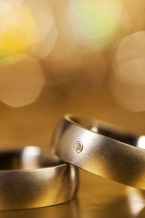 Closeup of wedding rings on golden background, with sparkling bokehの写真素材
