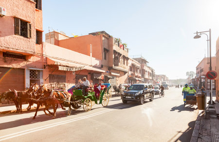 Marrakesh, Morocco: Horse drawn carriages, cars, cyclists and street cleaners on busy street at the Medinaのeditorial素材