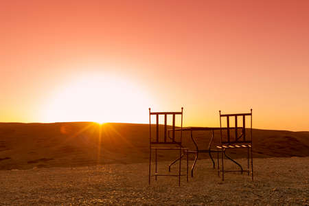 Tableand two chairs in the desert facing the siunsetの写真素材